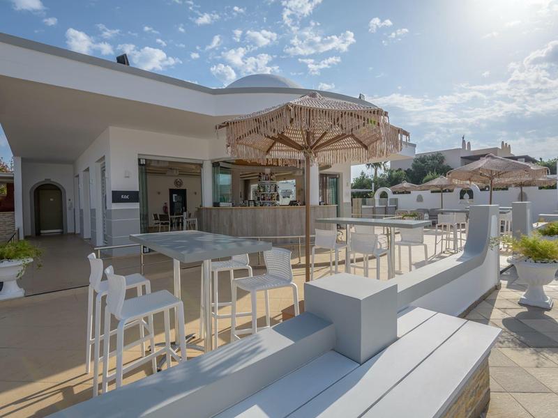 Área exterior del hotel con sombrillas y asientos bajo un cielo despejado