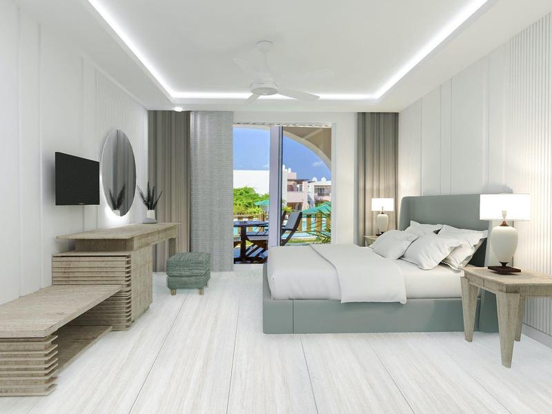 Moderna habitación de hotel luminosa con cama doble, TV, escritorio y balcón con vista al mar.