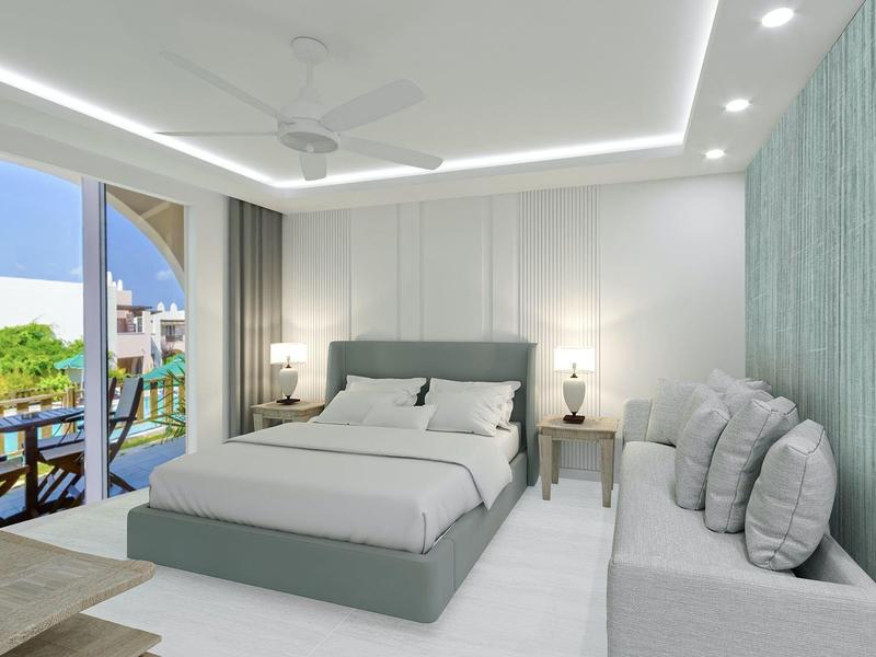 Habitación de hotel moderna con cama grande, sofá, mesas de noche y balcón con vista al mar.