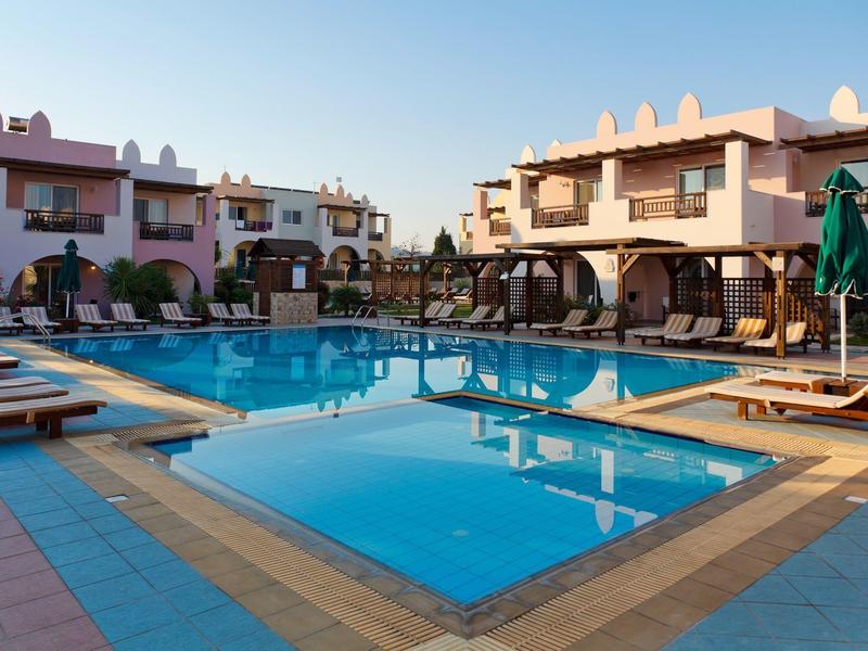 Área moderna de piscina del hotel con tumbonas y habitaciones dobles al fondo al atardecer.