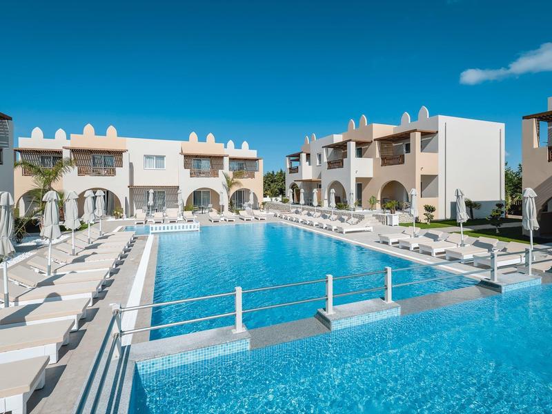 Piscina moderna de hotel con tumbonas y agua azul clara bajo un cielo despejado.