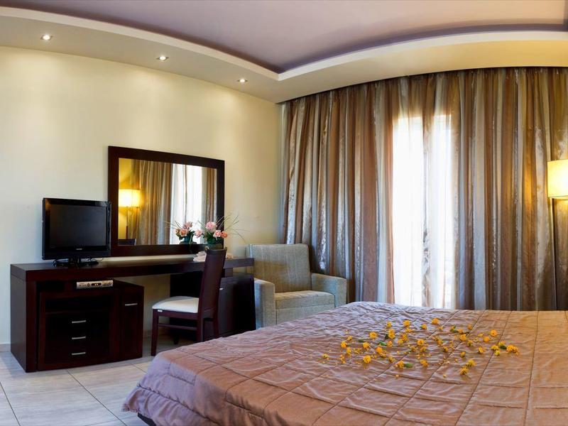 Acogedora habitación de hotel con cama grande, escritorio, televisor y cortinas en la ventana.