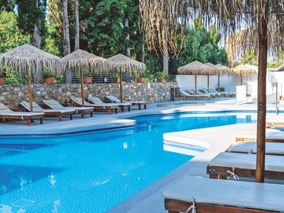 Ein klarer blauer Pool mit weißen Liegen und Sonnenschirmen in tropischer Gartenanlage.