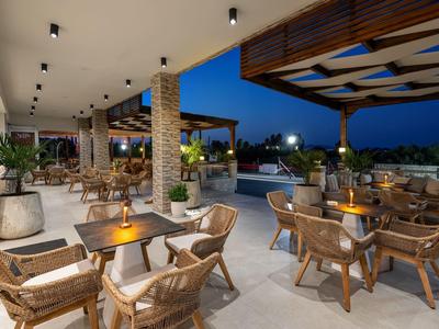 Gemütliche Hotelterrasse mit Korbsesseln, Tischen und Abendbeleuchtung unter freiem Himmel.