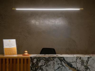 Moderne Hotelrezeption mit Marmor-Tresen, Serviceglocke und schlichter Beleuchtung.