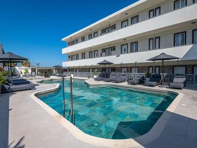 Moderner Hotelpool mit Liegestühlen und Sonnenschirmen unter klarem blauem Himmel.