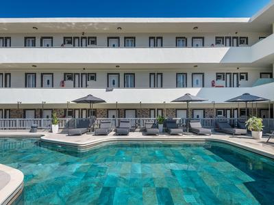 Moderner Hotelaußenpool mit blauen Fliesen und mehreren Liegestühlen bei strahlendem Himmel.