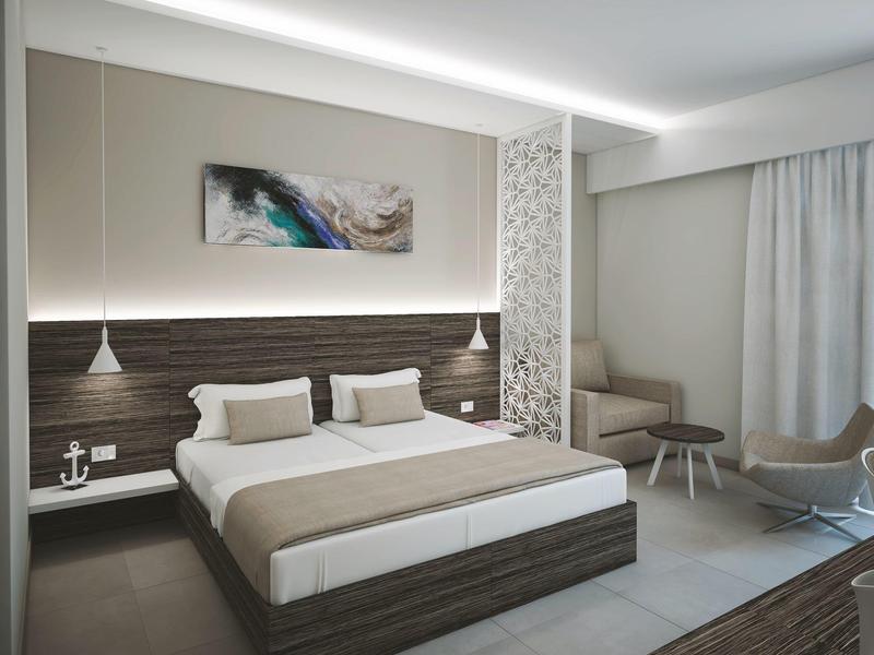 Moderní hotelový pokoj s manželskou postelí, nočními stolky, posezením a tlumenými barvami.