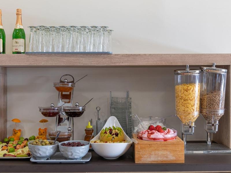 Bufet s šampaňským, sklenicemi, cereáliemi, ovocem a dezerty na hotelovém pultu.