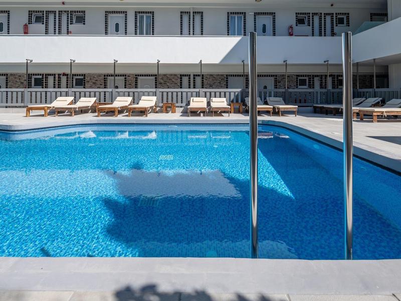 Moderní hotelový bazén s lehátky a zastíněnou terasou.