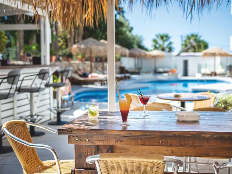 Příjemná terasa se stolem a nápoji s výhledem na hotelový bazén.