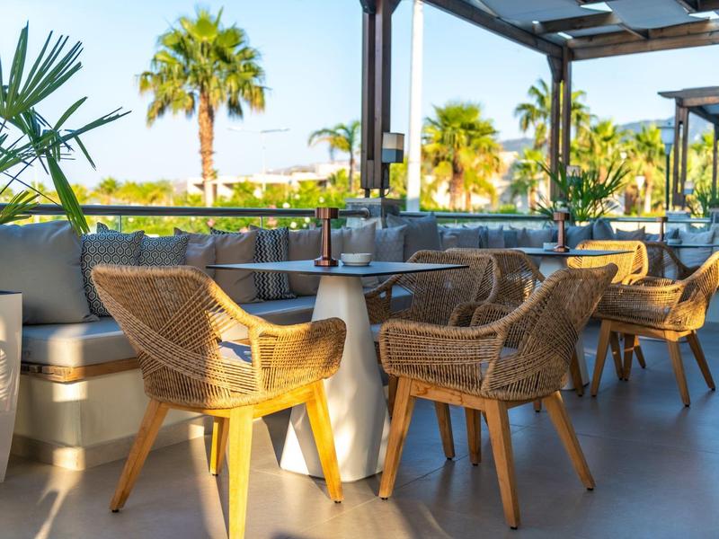 Pohodlné venkovní posezení s ratanovými židlemi a stoly, obklopené palmami