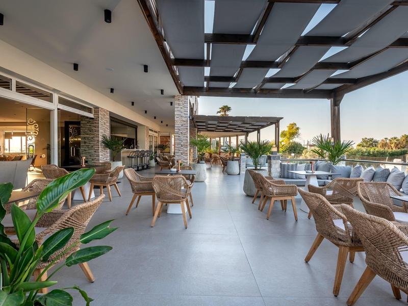 Moderní hotelová terasa s ratanovým nábytkem a rostlinami na slunném místě