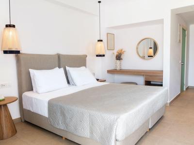 Modernes, helles Schlafzimmer mit großem Doppelbett, grauem Kopfteil, runden Holz-Nachttischen und hängenden Lampen.