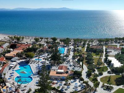 Luftaufnahme eines Urlaubsresorts mit Pools, grünen Flächen und Blick auf das blaue Meer.