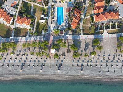 Luftaufnahme eines Strandes mit Promenade, Palmenreihen und blaugemustertem Schwimmbad.