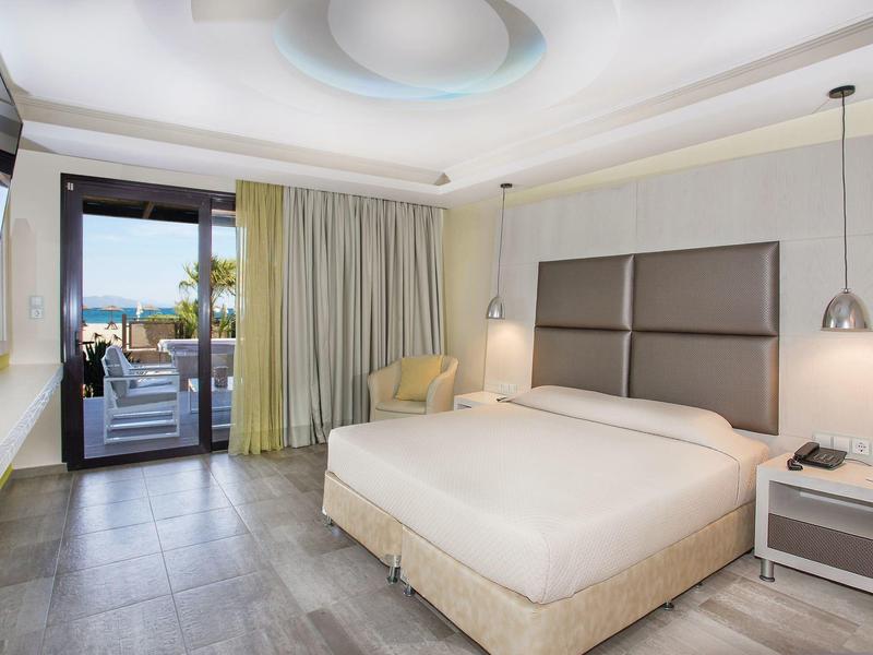 Moderní hotelový pokoj s manželskou postelí, balkonem a výhledem na moře za denního světla.