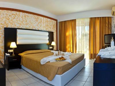 Moderne hotelkamer met groot bed, warme gordijnen en decoratieve handdoeken.