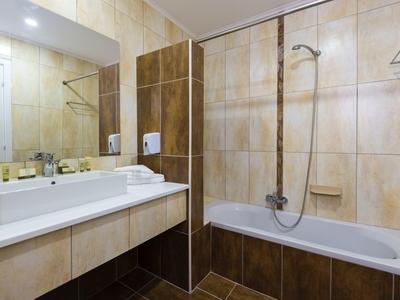 Moderne badkamer met bad, grote spiegel en wastafel.