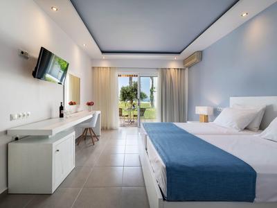 Moderne hotelkamer met groot bed en terras met uitzicht op zee.