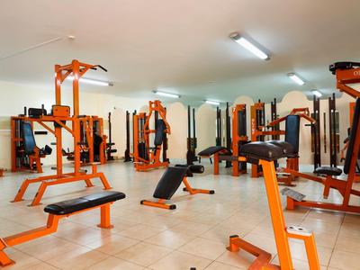 Großer Fitnessraum mit orangen Trainingsgeräten und hellen Wänden.