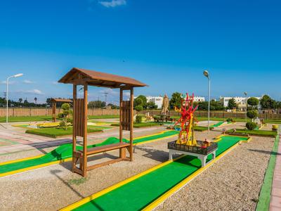 Minigolfanlage im Freien mit bunten Bahnen und Holzdach in einer offenen Landschaft.