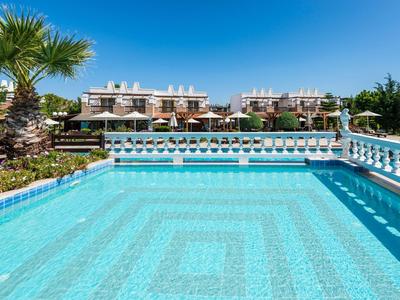 Schwimmbad mit klar blauem Wasser und Hotelgebäuden im Hintergrund unter blauem Himmel.