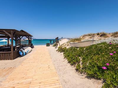 Holzsteg zum Strand mit Pavillon und Sanddünen unter klarem blauem Himmel