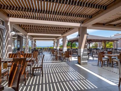 Überdachter Außenbereich eines Restaurants mit Holzmöbeln und Blick auf das Wasser