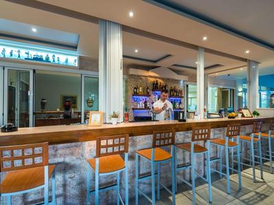 Moderner Hotelbarbereich mit hohen Stühlen und Barkeeper hinter der Theke.