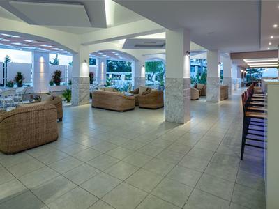 Lichte, modern ingerichte lounge met leren stoelen en barkrukken in een hotelhal.