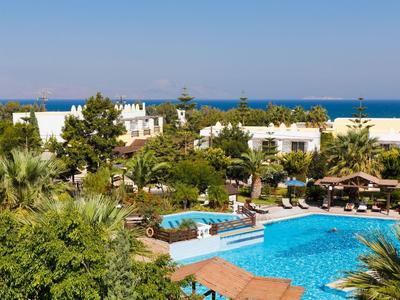 Hotelanlage mit großem Pool, Liegestühlen und Blick aufs Meer bei klarem Himmel
