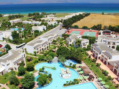 Resort met meerdere gebouwen, groot zwembad en zee op de achtergrond.