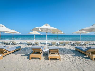 Wit zandstrand met ligstoelen en parasols aan de heldere blauwe zee.