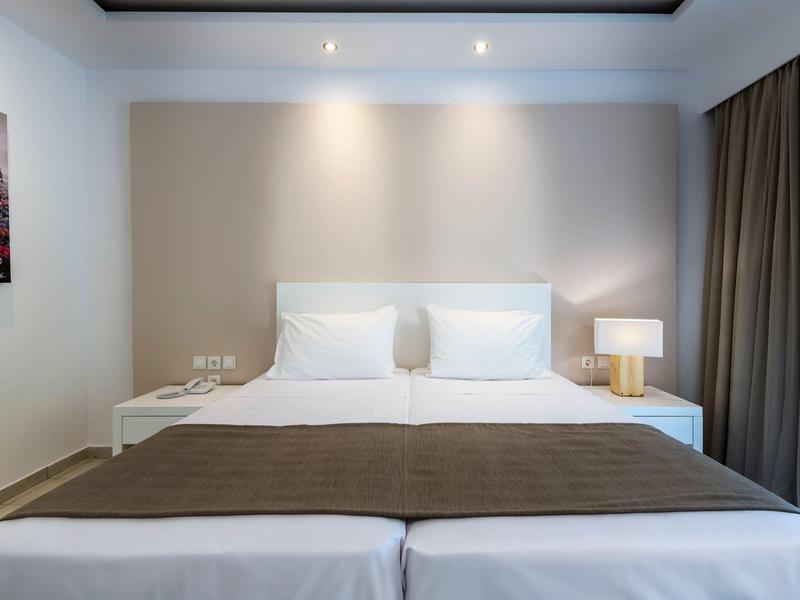 Schone hotelkamer met twee bedden, nachtkastjes en een lamp aan de muur.