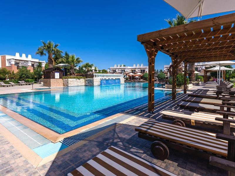 Zwembad met ligbedden en pergola in een zonnig hotelresort.