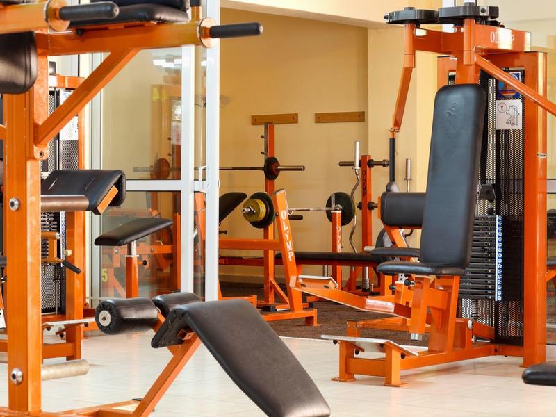 Sportschool met oranje fitnessapparatuur en spiegels aan de muur.