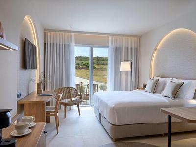 Lichte hotelkamer met tweepersoonsbed, balkon en moderne inrichting met zachte verlichting.