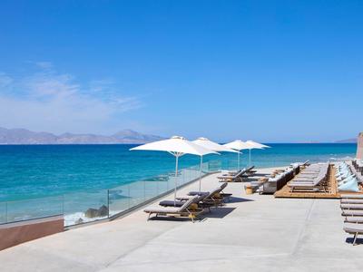 Strandgebied met ligstoelen en parasols naast rustige blauwe zee.
