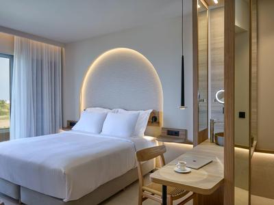 Moderne hotelkamer met groot bed, tafel, stoel en panoramisch raam met uitzicht.