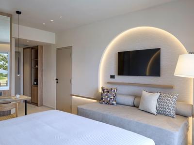 Modern hotelkamer met bed, bank, tv en grote booglamp.
