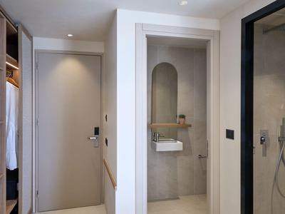 Moderne hotelgang met inloopkast, grijze deur en badkamer met glazen douche.