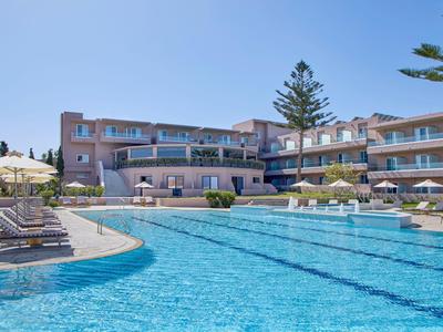Großer Außenpool mit Liegestühlen vor einem mehrstöckigen Hotel unter klarem Himmel.