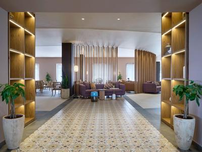 Moderner Hotellobby mit dekorativen Regalen, Pflanzen und gemütlichen Sitzbereichen.