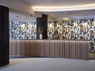 Moderne hotelreceptie met gebogen balie en abstracte wanddecoratie.