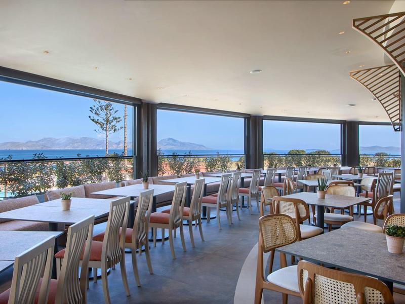 Modern restaurant met panoramische ramen met uitzicht op zee en bergen.