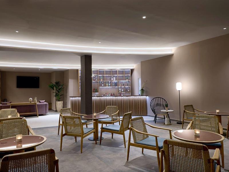 Moderne hotel lounge met stoelen, tafels en dimbare verlichting.