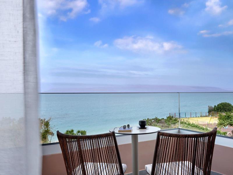 Balkon met twee stoelen en tafel met uitzicht op zee op een heldere dag.