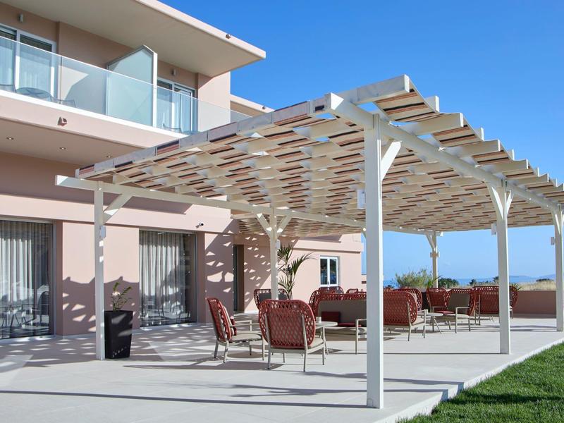 Moderne buitenruimte van een hotel met pergola, zitplaatsen en uitzicht op zee.