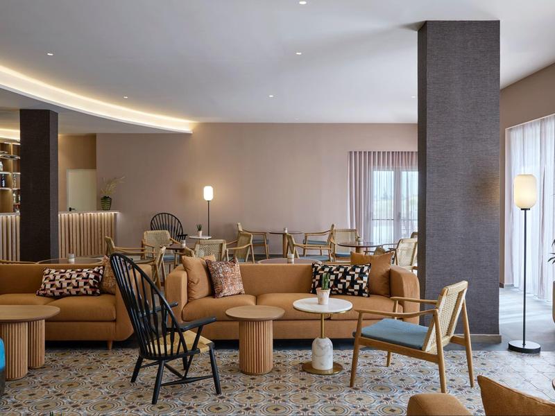 Modern ingerichte hotel lounge met banken, fauteuils en decoratieve kussens.